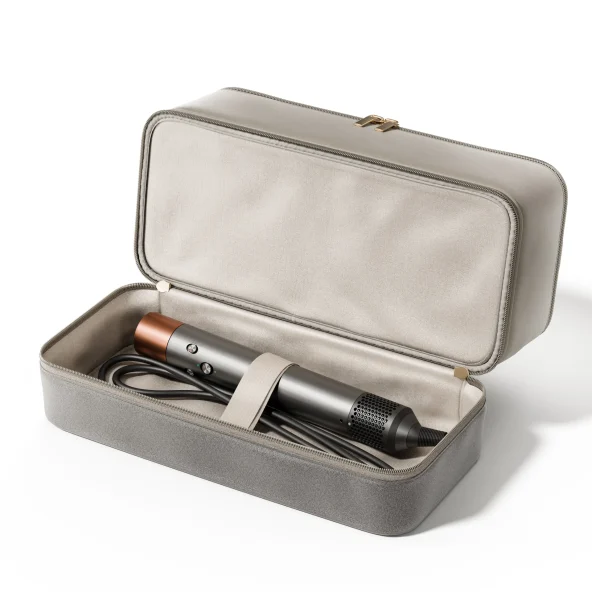 Open gray travel case holding a sleek black-and-copper hair dryer, secured with a strap alongside its coiled power cord.